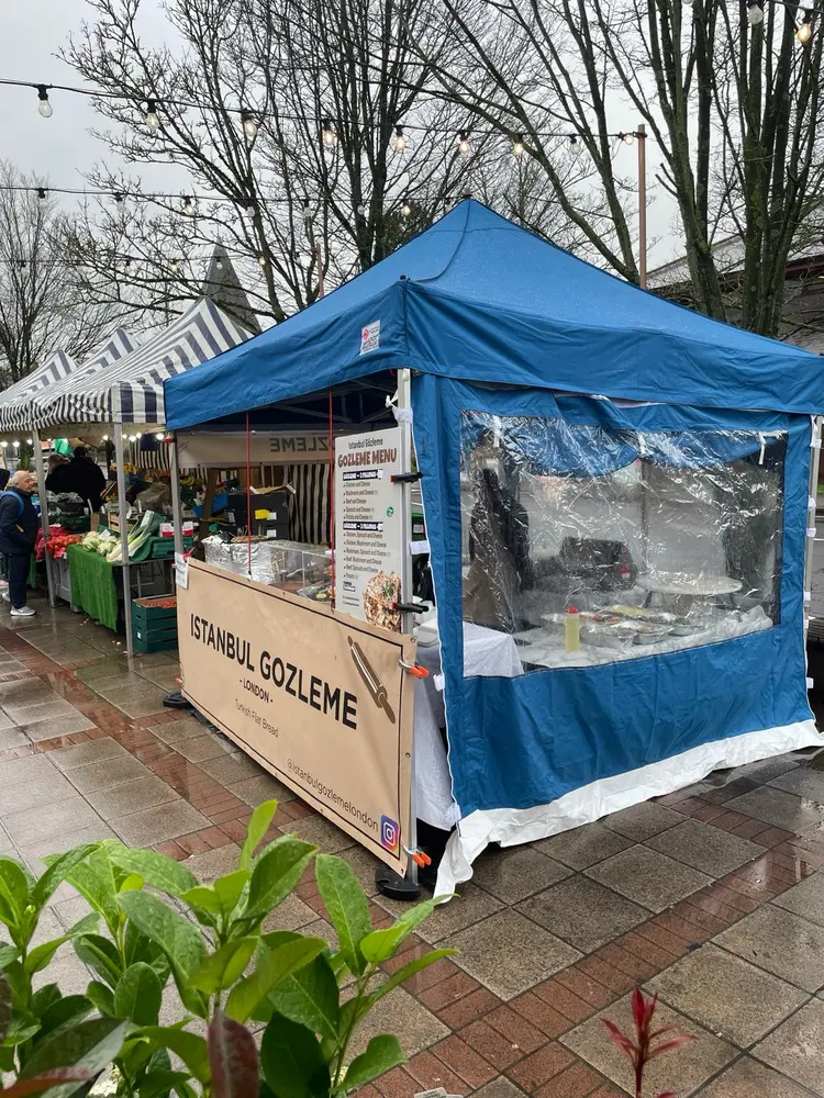The Istanbul Gozleme London gazebo on a rainy market day beside a fruit and veg stall